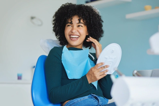 Woman with bright smile holding dental model in modern dental office setting.